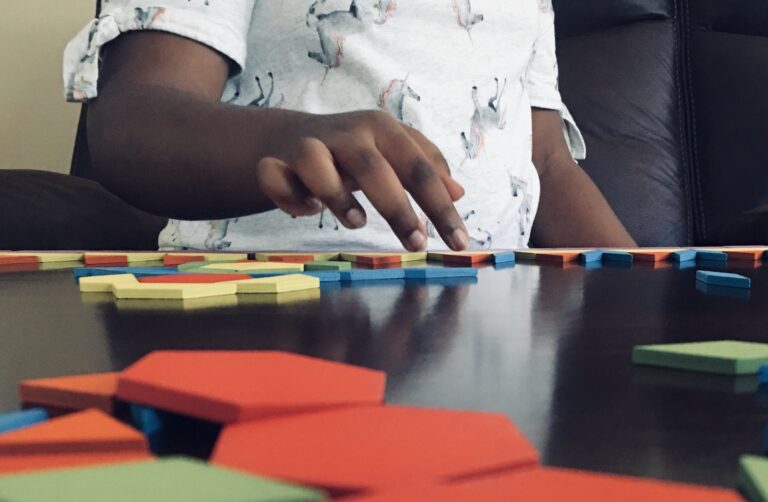 Young black girl playing with pattern blocks.